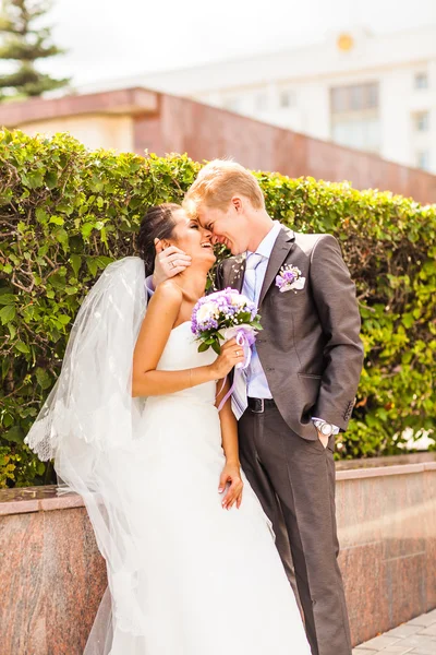 Bruidspaar knuffelen, de bruid met een boeket van bloemen in haar hand — Stockfoto