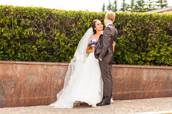 Casamento casal abraçando, a noiva segurando um buquê de flores em sua mão — Fotografia de Stock