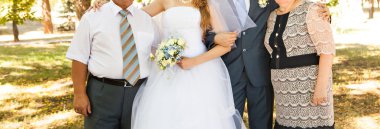 Yeni evli çift arka planda duran anne ile kucaklayan