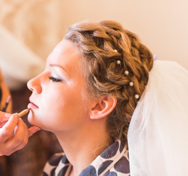 stylist maakt make-up bruid op de huwelijksdag