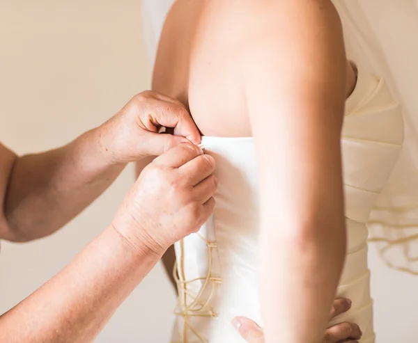 Dama de honra amarrando arco no vestido de noiva — Fotografia de Stock