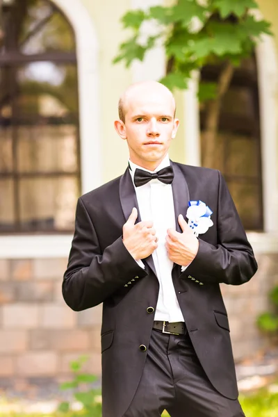 Novio guapo en esmoquin de boda sonriendo y esperando a la novia . — Foto de Stock