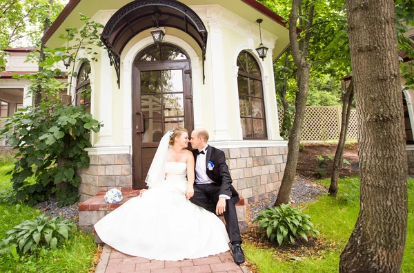 Pareja de boda sentada cerca de casa de verano —  Fotos de Stock