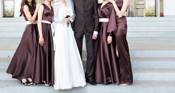 Beau marié en costume étreignant mariée élégante avec demoiselles d'honneur — Photo