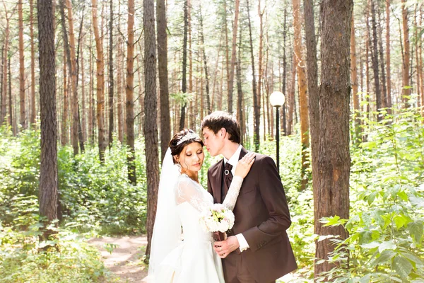 Hochzeitspaar umarmt, die Braut hält einen Blumenstrauß in der Hand — Stockfoto
