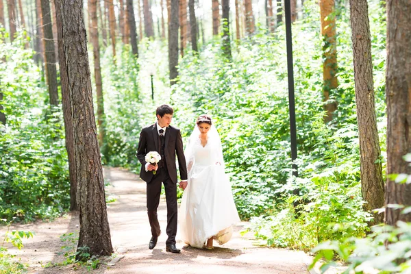 Gelukkige bruid en bruidegom lopen in zomer bos. Jonge bruidspaar. — Stockfoto