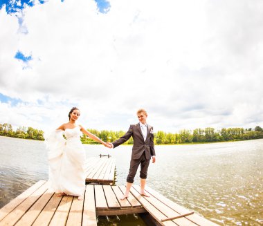 Güzel gelin ile damat bir gölün yanında. Öp ve birbirlerine sarılmak