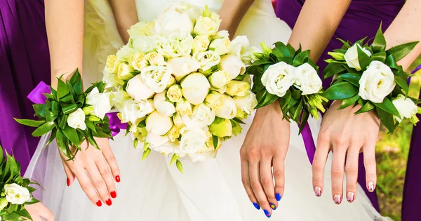 De bruid en de bruidsmeisjes tonen mooie bloemen op hun handen — Stockfoto