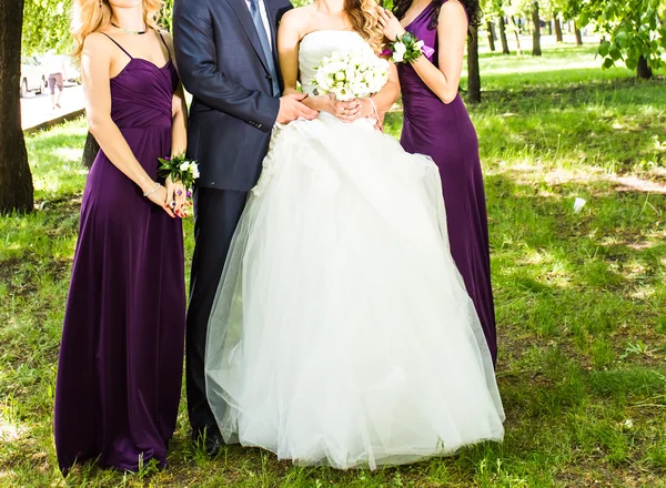 Menyasszony a vőlegény és koszorúslány fák közelében — Stock Fotó