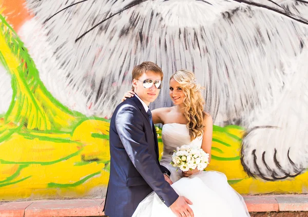 bride and groom holding hands on graffiti wall background