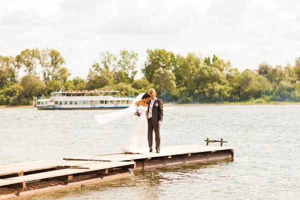 Bruidspaar op de pier in de buurt van grote lake — Stockfoto