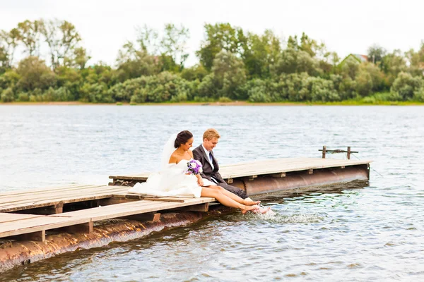 Casal de casamento no cais perto de grande lago — Fotografia de Stock