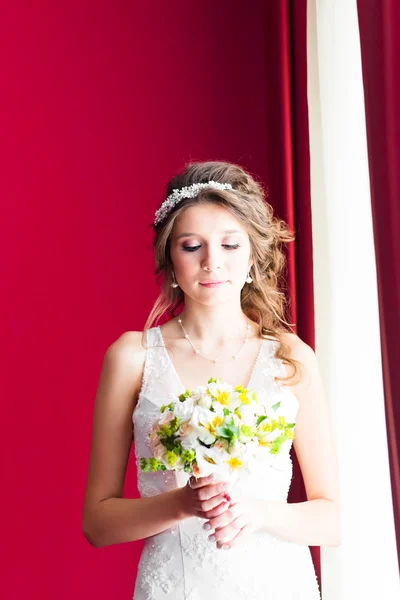 Красивая молодая невеста со свадебным макияжем и прической в спальне — стоковое фото