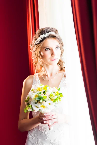 Schöne junge Braut mit Hochzeits-Make-up und Frisur im Schlafzimmer — Stockfoto