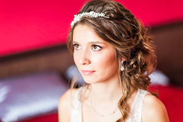 Mooie jonge bruid met bruiloft make-up en haarstijl in slaapkamer — Stockfoto