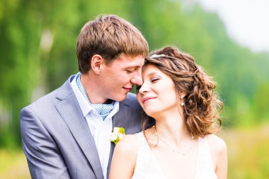 genç güzel düğün çifti çimen bir alana sarılma.