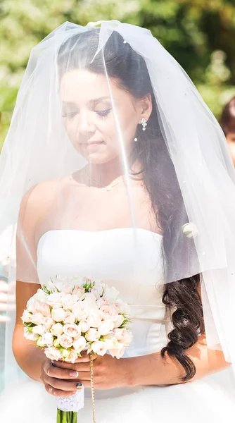 Ernste junge Braut in Schleier mit Blumenstrauß — Stockfoto