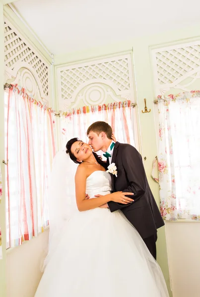 Счастливые улыбающиеся молодожены веселятся и целуются на свадьбе . — стоковое фото