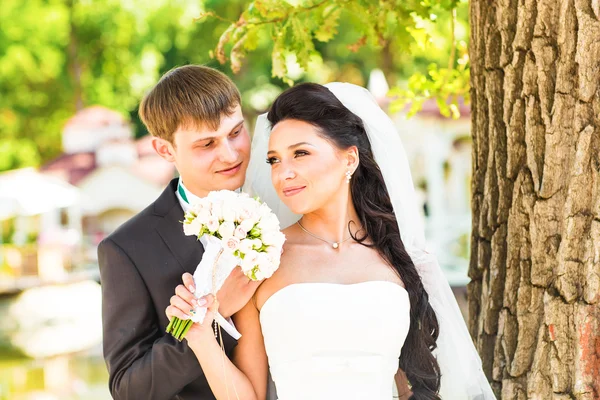 幸せ楽しい新婚夫婦を笑顔と結婚式の日に屋外キス. — ストック写真