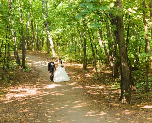 Panny młodej i pana młodego na chodzenie na zewnątrz dzień ślubu. Nowożeńcy w parku. — Zdjęcie stockowe