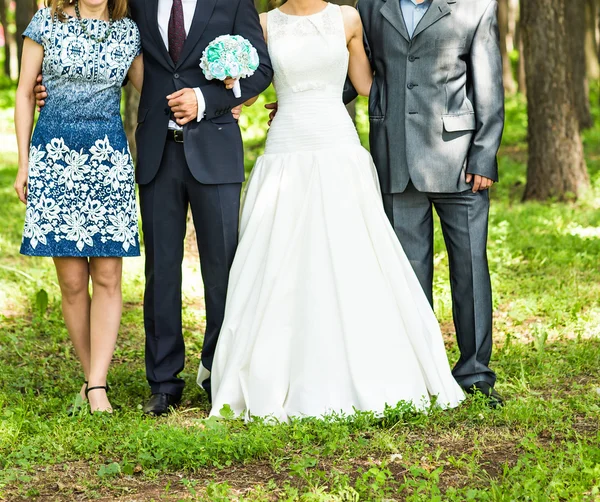 Couple nouvellement marié avec des invités dans un parc vert ensoleillé — Photo