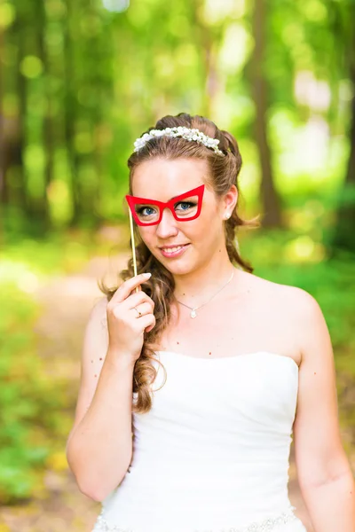 April Fools Day. Bride posing with stick lips, mask.