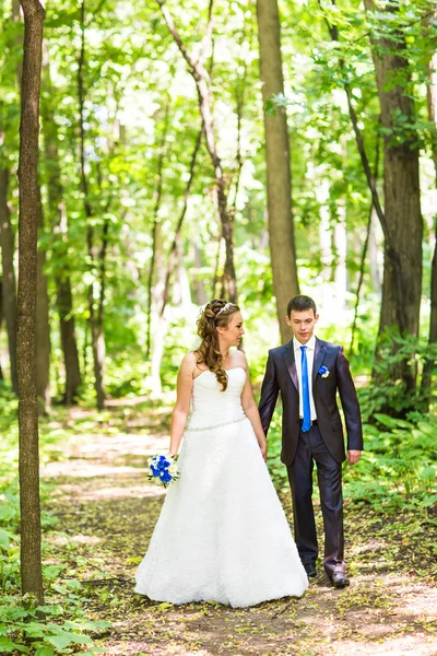 Couple nouvellement marié marcher sur les sentiers du parc se tenant la main — Photo