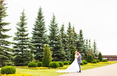 Şık gelin ve damat düğün günü dışarıda birlikte poz veriyorlar.