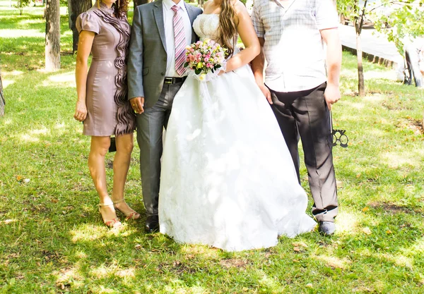 Bruden och brudgummen står med gäster i trädgården — Stockfoto