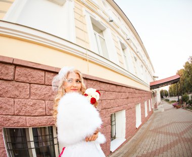 Gelinlikli genç gelin elinde buket tutuyor.