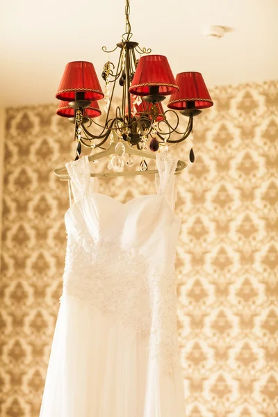 Wunderschönes Brautkleid, das an einer Lampe im Zimmer hängt. Brautmorgen. — Stockfoto