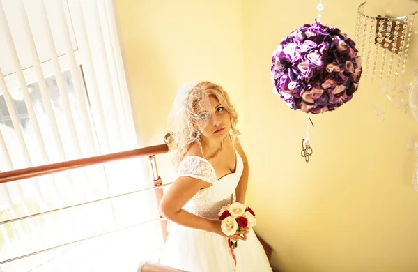 Mladá nevěsta ve svatebních šatech drží kytice — Stock fotografie