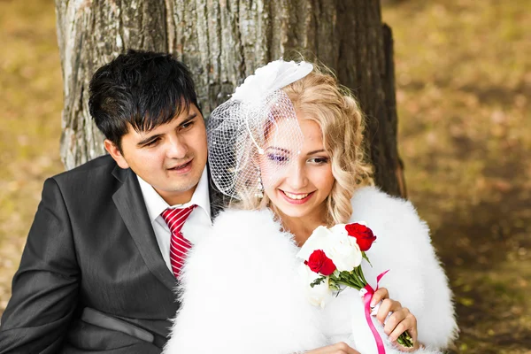 Bröllop par kramande, bruden håller en bukett blommor i hennes hand, brudgummen omfamna henne — Stockfoto