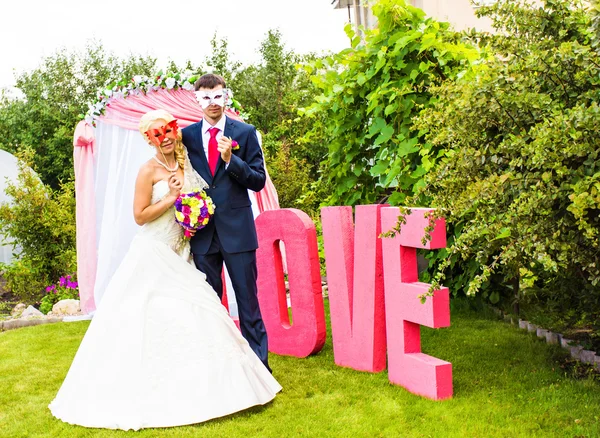 Bride and groom with funny carnival masks — Stock Photo, Image