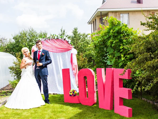 Gelukkige bruid en bruidegom met letter het woord liefde — Stockfoto