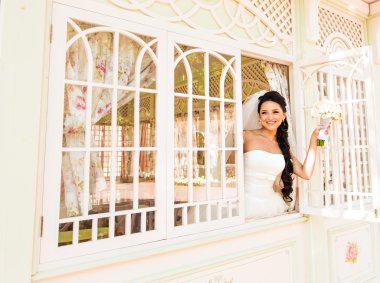 Gelinlikli genç gelin elinde buket tutuyor.