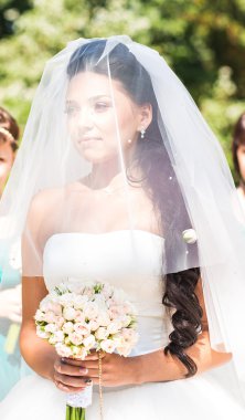 Genç gelin gelinlik ve buket tutan peçe