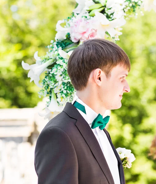 Elegante noivo elegante ter cerimônia de casamento no fundo do arco — Fotografia de Stock