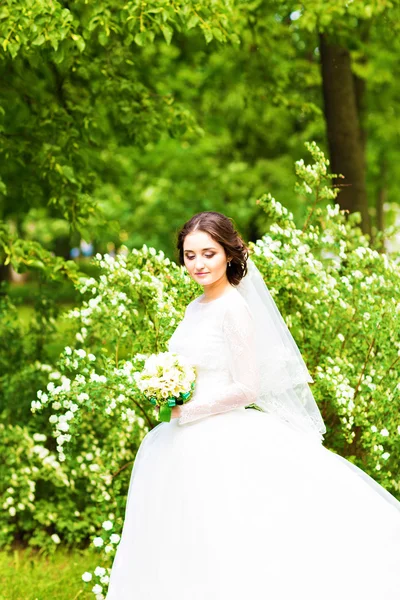 Bela noiva com buquê de casamento de flores ao ar livre no parque da primavera . — Fotografia de Stock