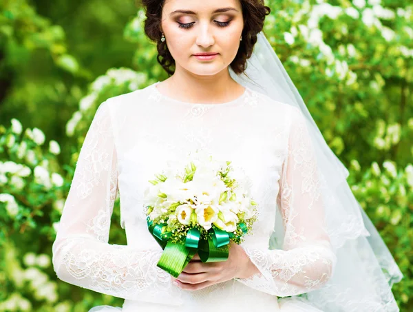 Schöne Braut mit Hochzeitsstrauß von Blumen im Freien im Frühling Park. — Stockfoto