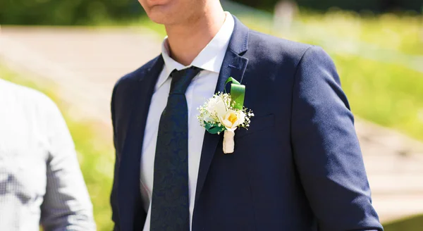 Le marié en costume bleu avec une boutonnière de fleurs et de verdure — Photo