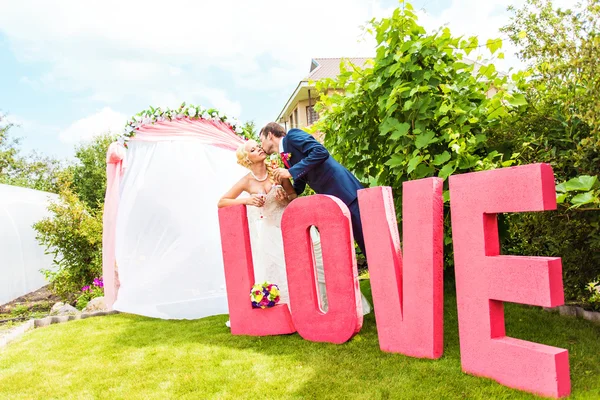 Bruid en bruidegom in de buurt van de brief het woord liefde, woord liefde samengesteld uit letters — Stockfoto