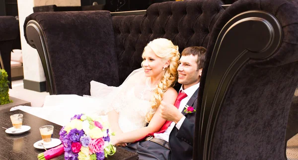 Жених и невеста обнимаются. Новобрачные сидят на диване и обнимаются — стоковое фото