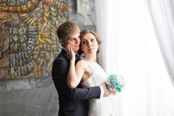 Vackra bruden och brudgummen nära fönstret. — Stockfoto