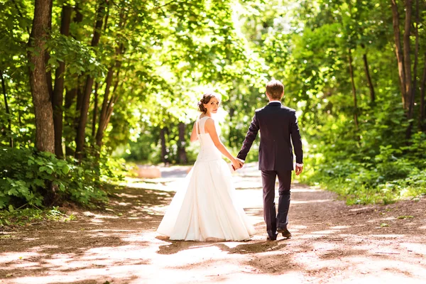 Mariée et marié marchant loin dans le parc d'été en plein air — Photo