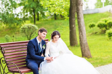 Mutlu bir gelin ile damat bir bankta oturan portresi