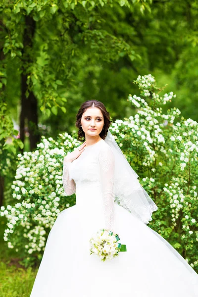 Bela noiva com buquê de casamento de flores ao ar livre no parque da primavera . — Fotografia de Stock