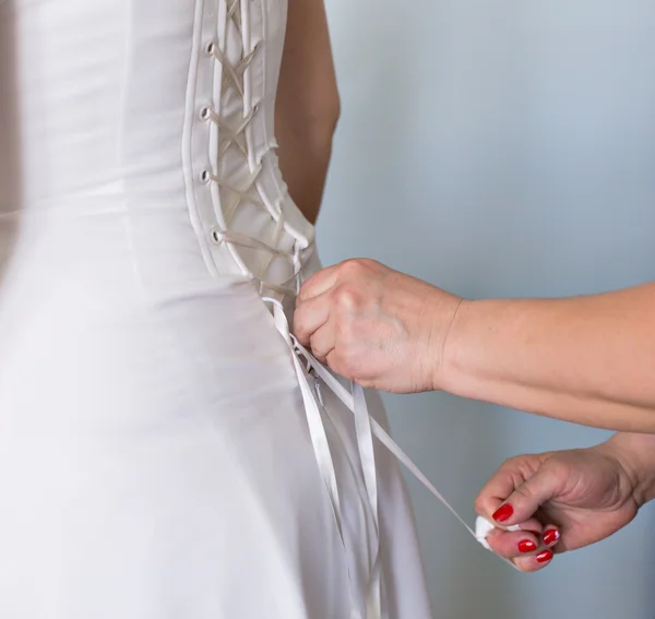 Bridesmaid tying bow on wedding dress — Stock Photo, Image