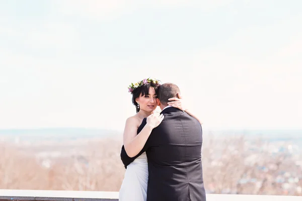 Casal jovem elegante bonito está abraçando no topo da colina com vista incrível pitoresca no céu brilhante de verão — Fotografia de Stock