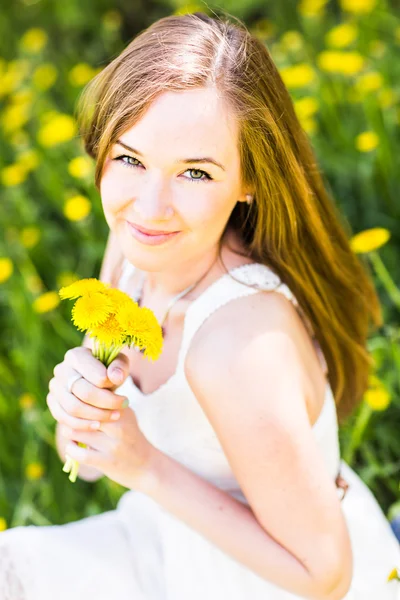 Portrait de belle fille avec bouquet de pissenlits jaunes en plein air en été, se concentrer sur les yeux — Photo